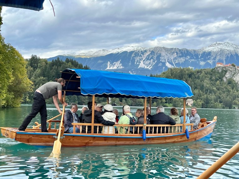 "Pletna" boats with standing oarsmen are the traditional way to get to The Pilgrimage Church of the Assumption of Mary on Lake Bled in Slovenia.
