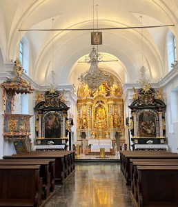 "The Wishing Bell" rope at the Pilgrimage Church of the Assumption of Mary hangs in front of the pews. Below the rope is a window to medieval graves beneath the floorboards. The frescoes survived the earthquake in the earlier Gothic church.